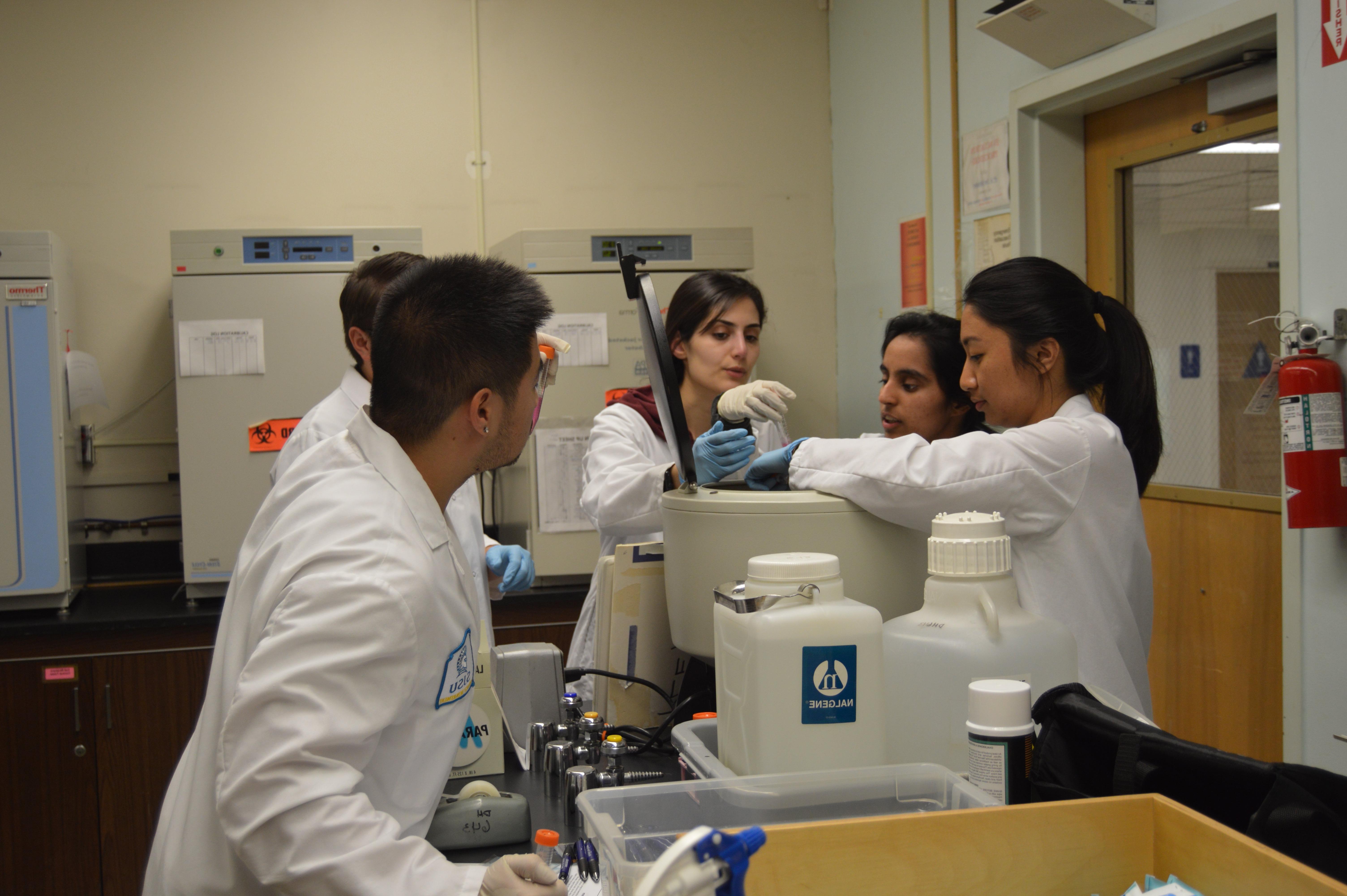 A group of students, some wearing lab coats