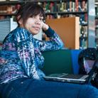 Woman sitting with a laptop on her lap in a library