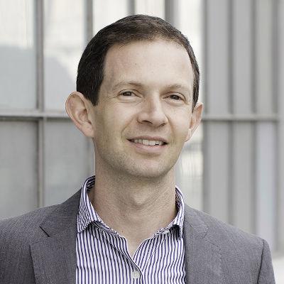 A smiling man with short hair wearing a suit